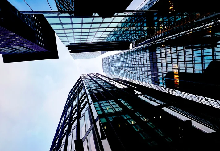 Looking up at Tall Buildings in a City Skyline During a Cloudy Day With Reflections on Glass Surfaces